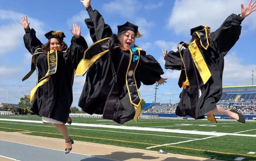 Three Doctor of Nursing Practice graduates jump in the air during commencement.