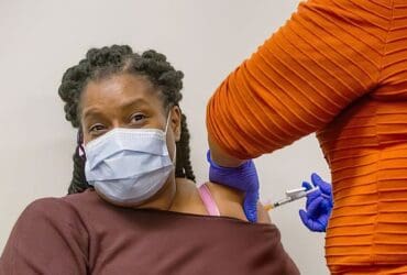 Photo of a woman wearing her mask while getting her vaccine.