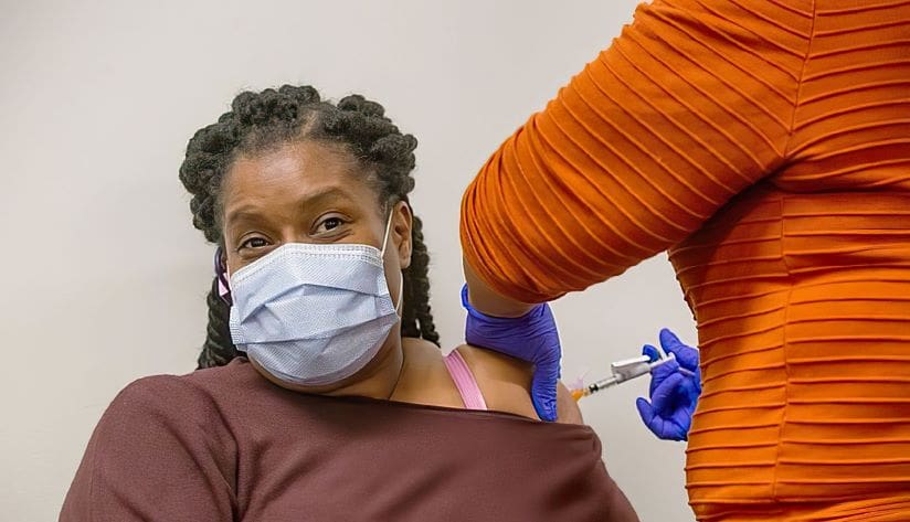 Photo of a woman wearing her mask while getting her vaccine.