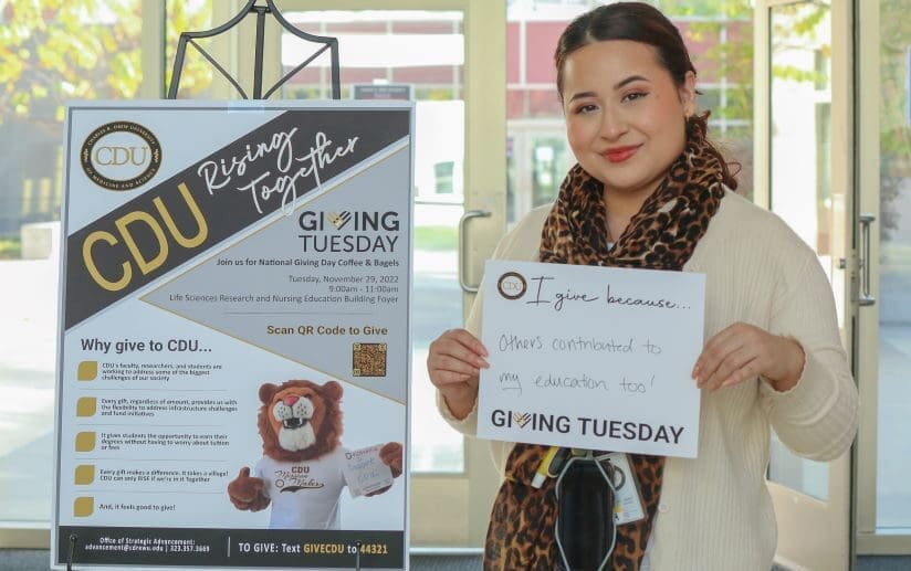 CDU staff members holds sign saying "I give back because other contributed to my education too" during CDU Giving Tuesday.