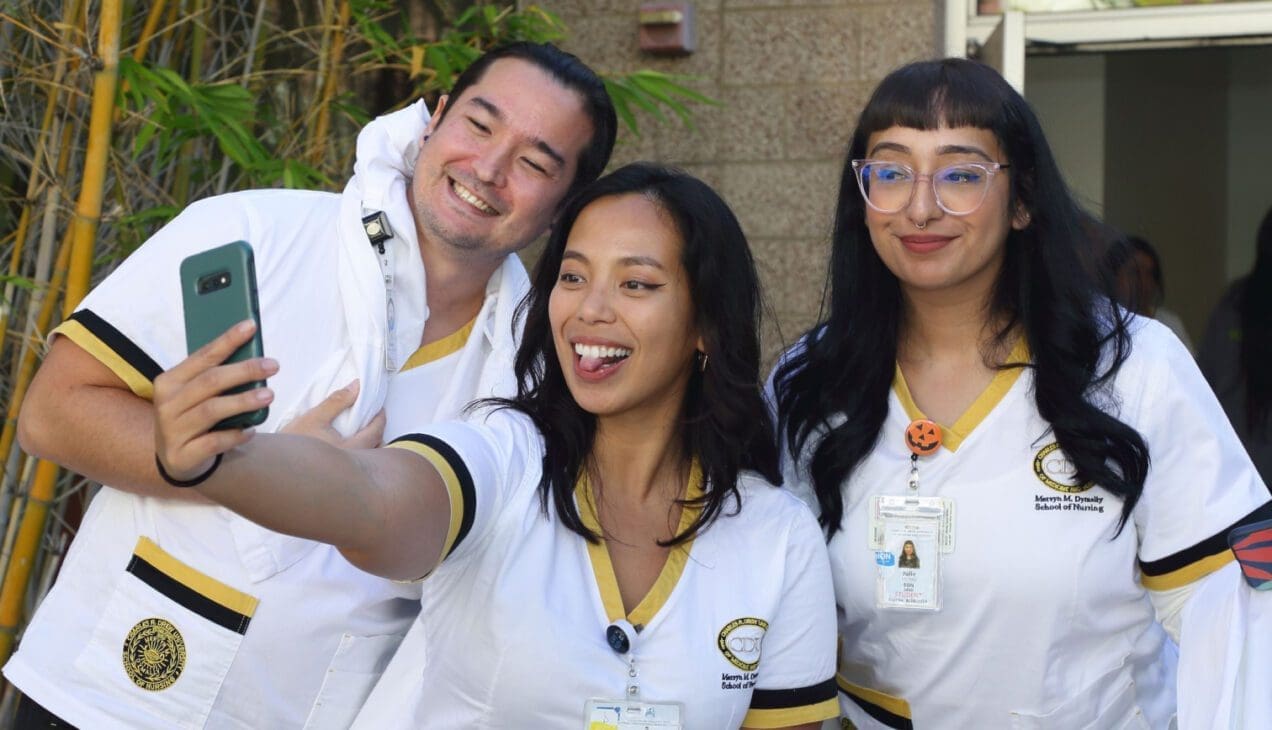Three CDU students wearing scrubs take a selfie