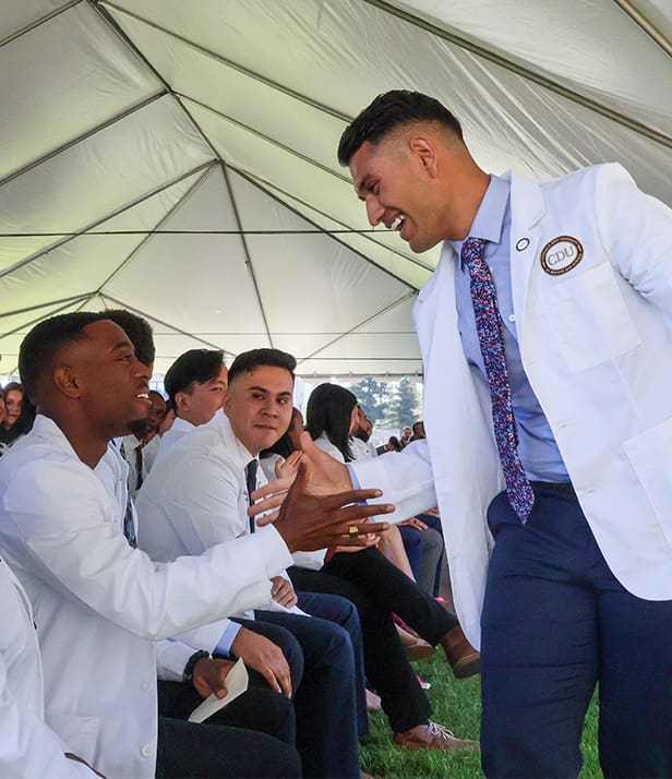 students shake hands during white coat ceremony