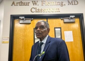 Dr. Arthur W. Fleming poses in front of the classroom named after him
