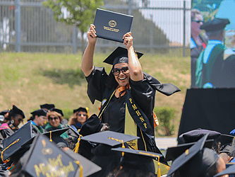 CDU student holds up diploma during commencement