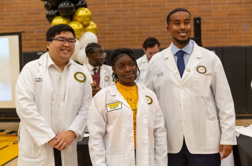 SSA student in white coat with SSA instructors