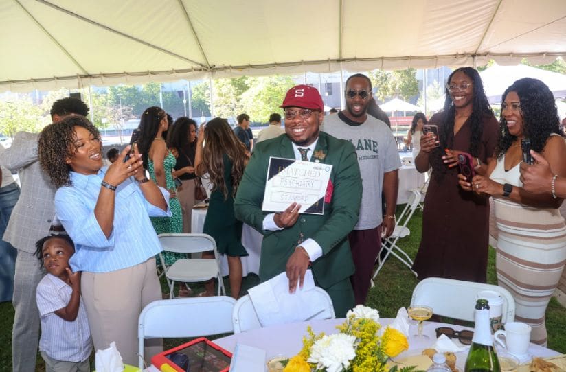 student holding up Match Day results surrounded by family
