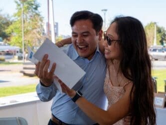 student holding match letter while being hugged by family