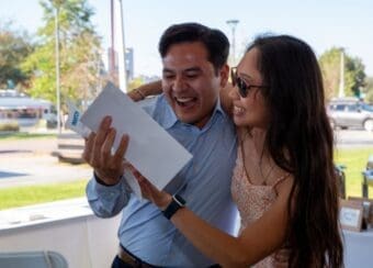 student holding match letter while being hugged by family