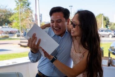 student holding match letter while being hugged by family