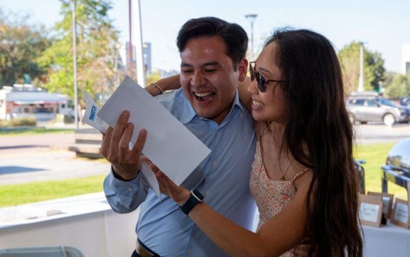 student holding match letter while being hugged by family