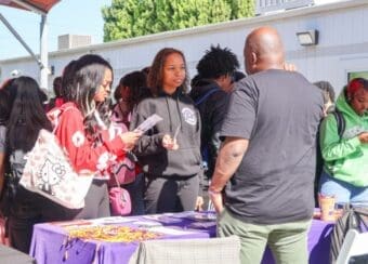 students in black and red hoodie holding brochures