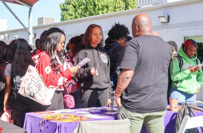 students in black and red hoodie holding brochures