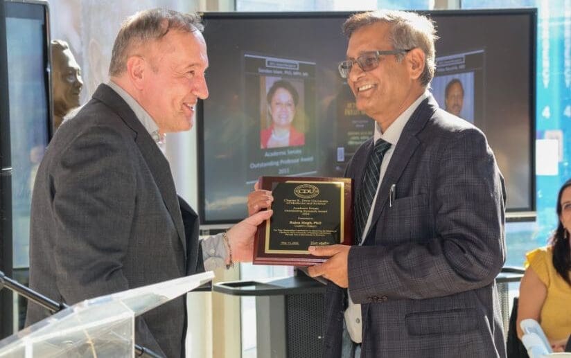 Faculty members holding plaque