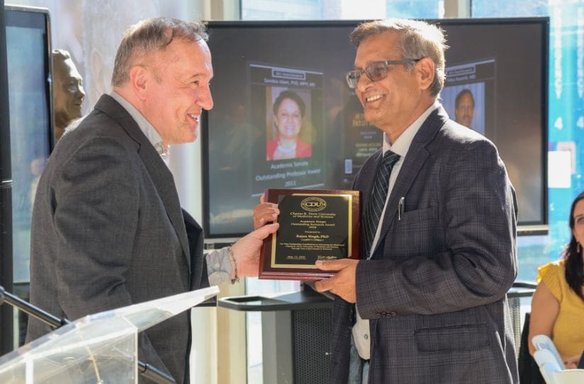 Faculty members holding plaque