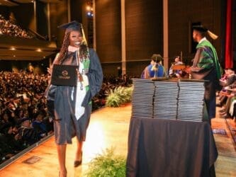 student-wearing-regalia-and-holding-degree