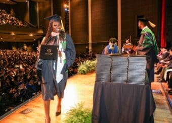 student-wearing-regalia-and-holding-degree