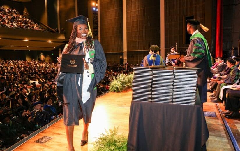 student-wearing-regalia-and-holding-degree