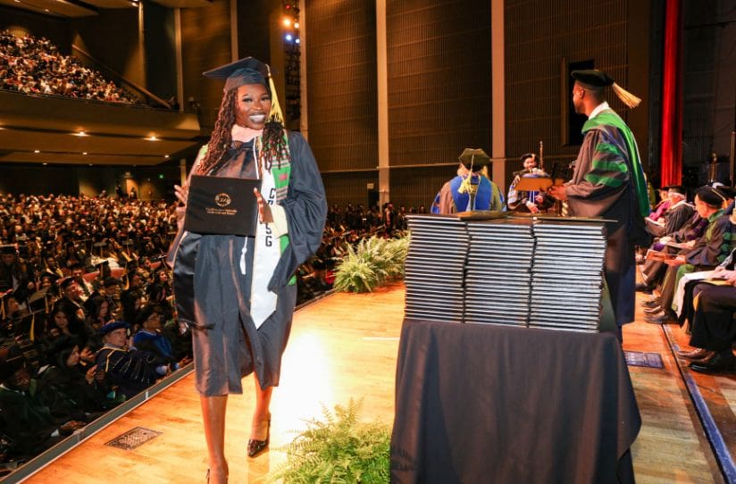 student-wearing-regalia-and-holding-degree
